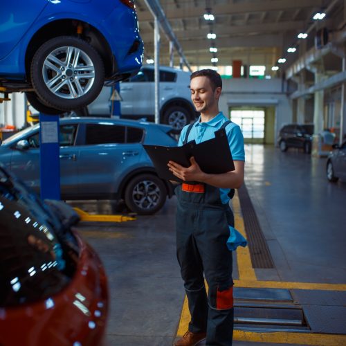 Worker with a checklist, car service station